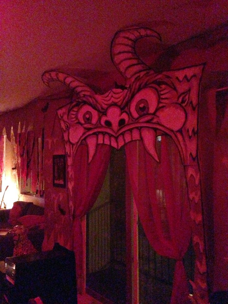 a living room decorated in pink and red with an elaborate dragon mask on the wall