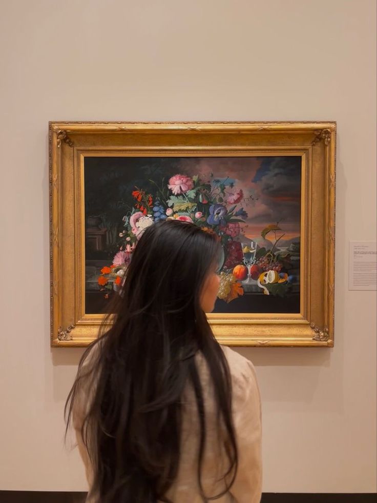 a woman standing in front of a painting with long black hair looking at it's reflection