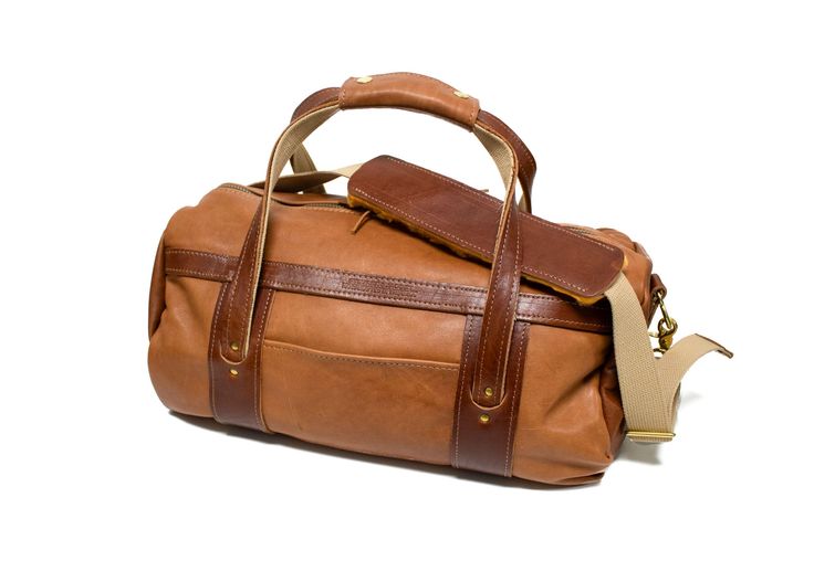 Natural Leather with Chestnut Leather Trim Made from hand-selected American tanned hides & American sourced brass hardware, our Steurer & Jacoby® Club Duffel Bags are perfect for going to the club, on a short get-away or on an outdoor adventure. Includes a free matching luggage tag ($25 value). Full Length Zipper Closure Deluxe Adjustable Sling Leather Handle Wrap Exterior Zippered Passport Pocket Easy Access Exterior Pocket Meets standard TSA Carry-on Regulations Measurements: 10”H x 8”D x 18”W Cognac Satchel With Brass Hardware For Daily Use, Luxury Brown Satchel With Brass Hardware, Classic Saddle Shoulder Bag With Leather Trim, Leather Saddle Satchel With Leather Handles, Cognac Bag With Brass Hardware For Everyday Use, Travel Satchel In Cognac Vegetable Tanned Leather, Cognac Vegetable Tanned Leather Satchel For Travel, Cognac Leather Bag With Brass Hardware, Leather Weekender Bag In Cognac With Smooth Grain