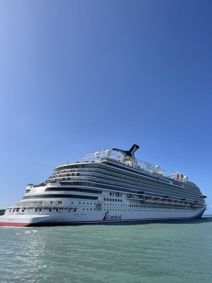 a large cruise ship in the middle of the ocean with clear blue skies above it