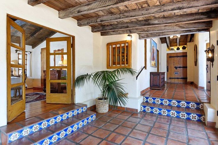 an entry way with blue and white tiles on the floor, potted plant in front