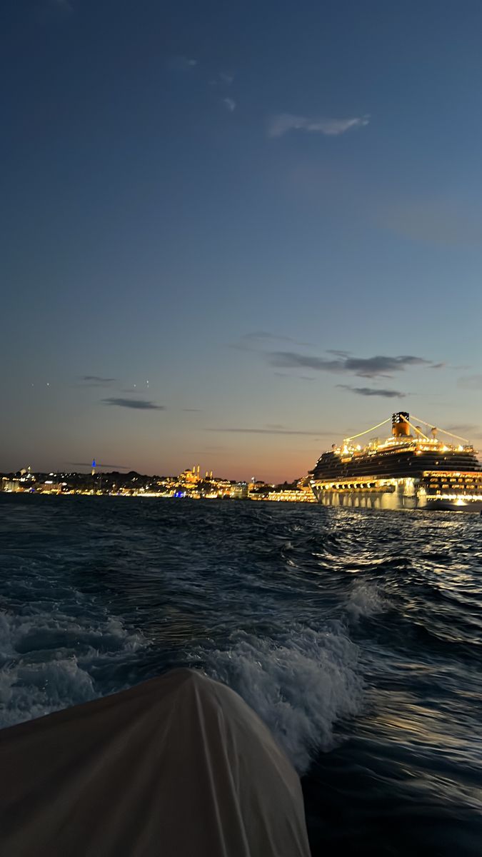 a cruise ship is in the distance as it sails through the water at night time