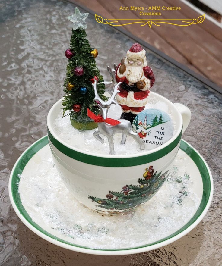 a santa clause figurine sitting on top of a cup filled with water and snow