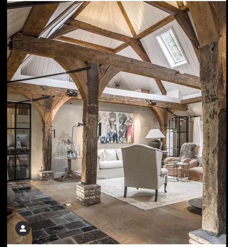 a living room filled with furniture and stone flooring under a wooden beamed ceiling