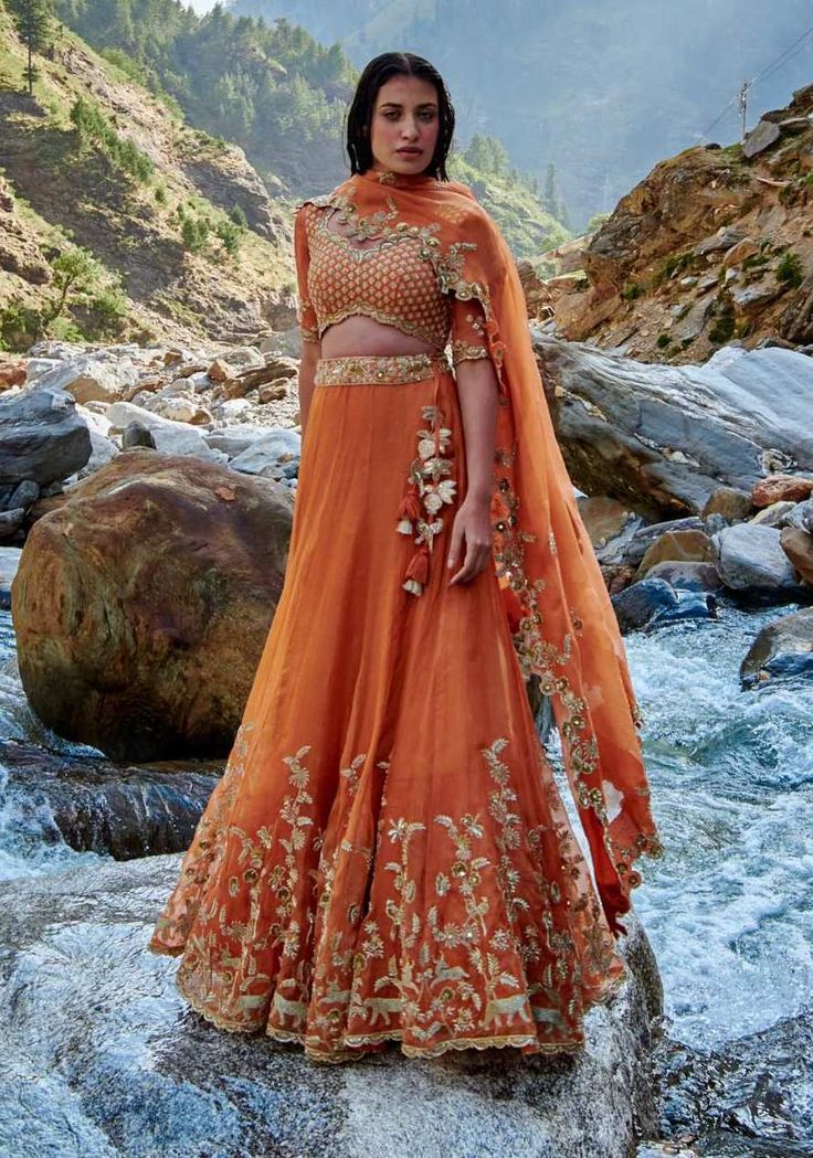 Editor's Note Relishing The Sunshine And Nature, Our Sherbet Orange Lehenga Features Forest Inspired Hand Embroidery Embellished With Zari Work, Sequins, Moti And Dabka Work Paired With the Same Embroidered Blouse And Dupatta Color: Orange Fabric: Tissue Care: Dry Clean Only About the Designer Paulmi & Harsh is a luxury prêt label inspired by beautiful botanicals. Paulmi & Harsh design strong, feminine silhouettes with prints and delicate detailing, fusing 1950’s fashion with modern-day sensibil Orange Color Lehenga, Pastel Orange Lehenga, Reception Embroidered Chinon Sets, Embroidered Chinon Sets For Reception, Traditional Embellished Saree Set, Semi-stitched Embellished Lehenga For Transitional Season, Transitional Semi-stitched Embellished Lehenga, Festive Orange Embellished Sets, Embellished Fitted Traditional Sets