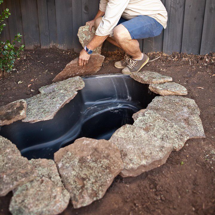 a man squatting down next to a hole in the ground that is filled with water