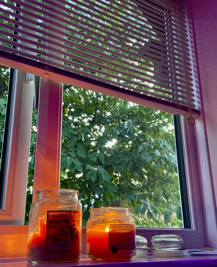 two jars filled with liquid sitting on top of a window sill