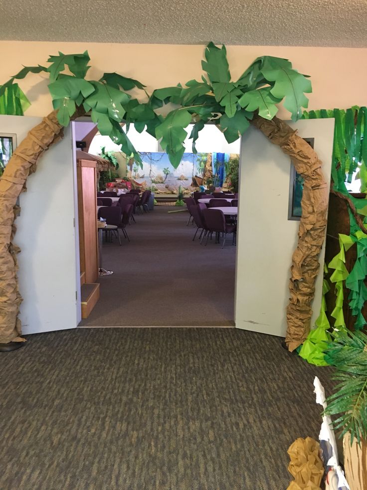 an entrance to a restaurant decorated with fake trees and leaves on the walls, along with tables and chairs