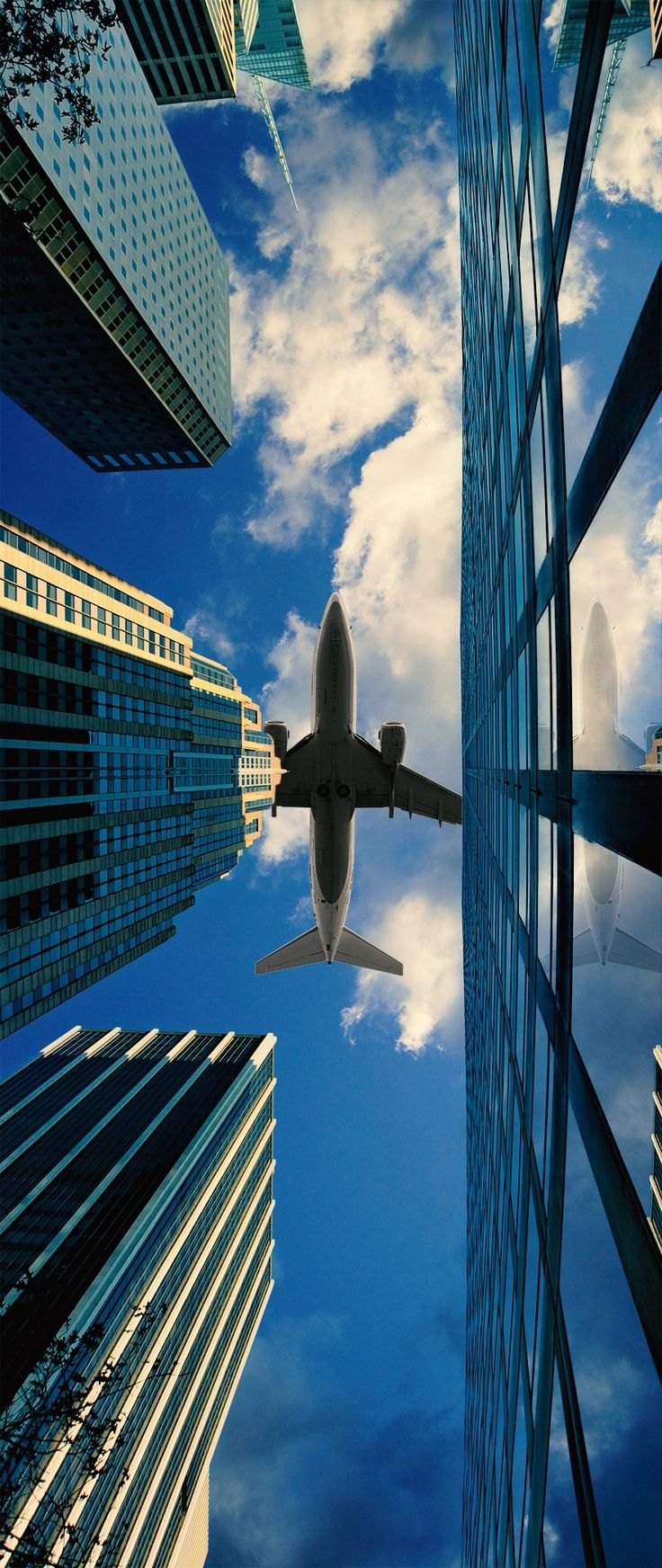 an airplane is flying in the sky between tall buildings