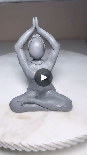 a statue of a person doing yoga on top of a white tableclothed surface