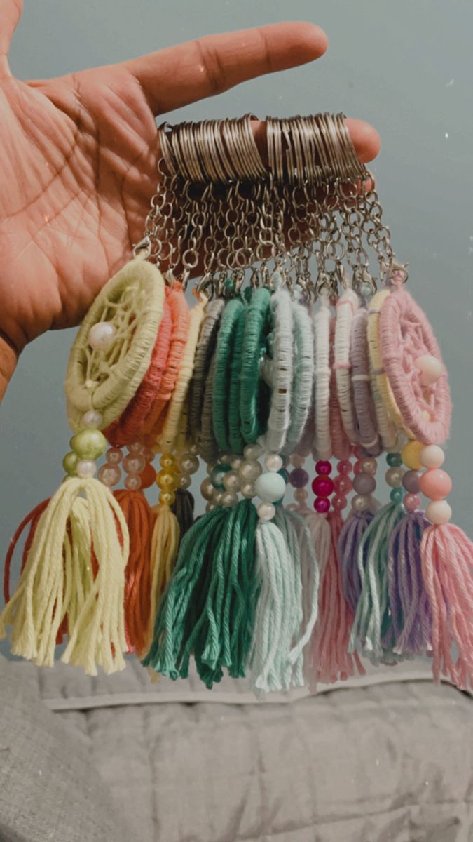 a hand is holding several bracelets with tassels