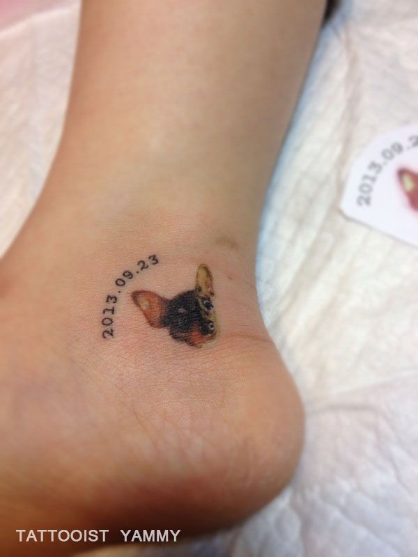 a small dog tattoo on the foot of a woman's leg with words written below it