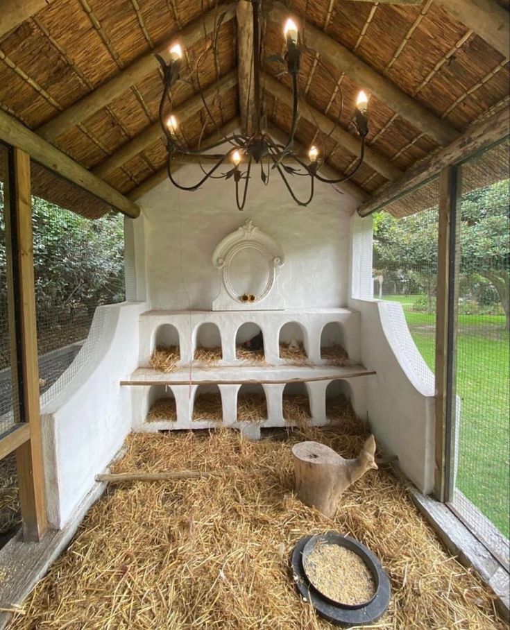 the inside of a chicken coop with hay on the floor and lights hanging from the ceiling