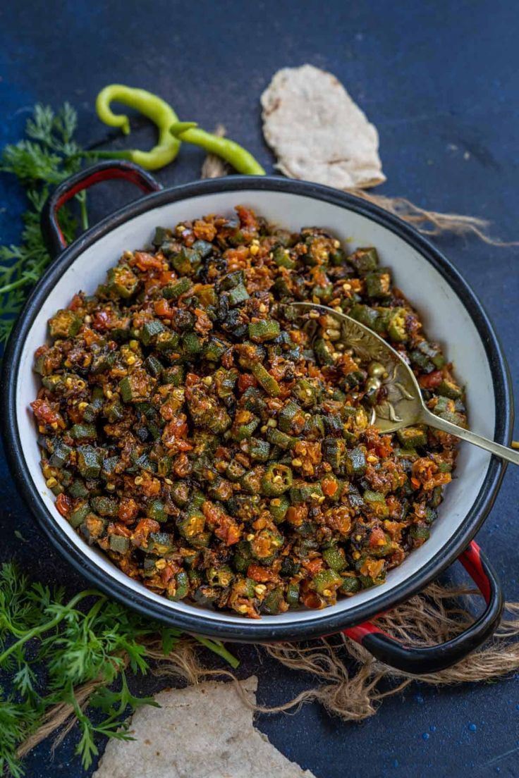 a bowl full of food with a spoon in it and the words bhindi masala above it