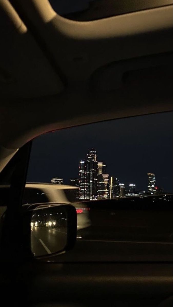 the view from inside a car at night with city lights in the background