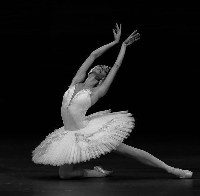 a ballerina in white tutu with her arms stretched out to the side, stretching