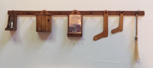 a wall mounted shelf with wooden items hanging from it's sides and two brooms on the other side