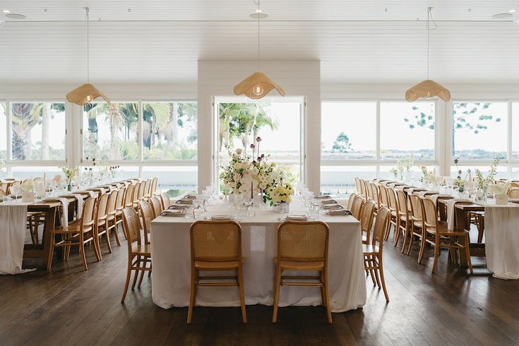 a dining room with tables and chairs set up for a formal function in front of large windows