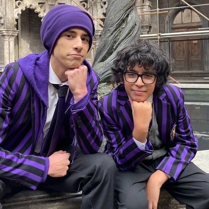 two people sitting next to each other wearing purple and black striped jackets with hoods