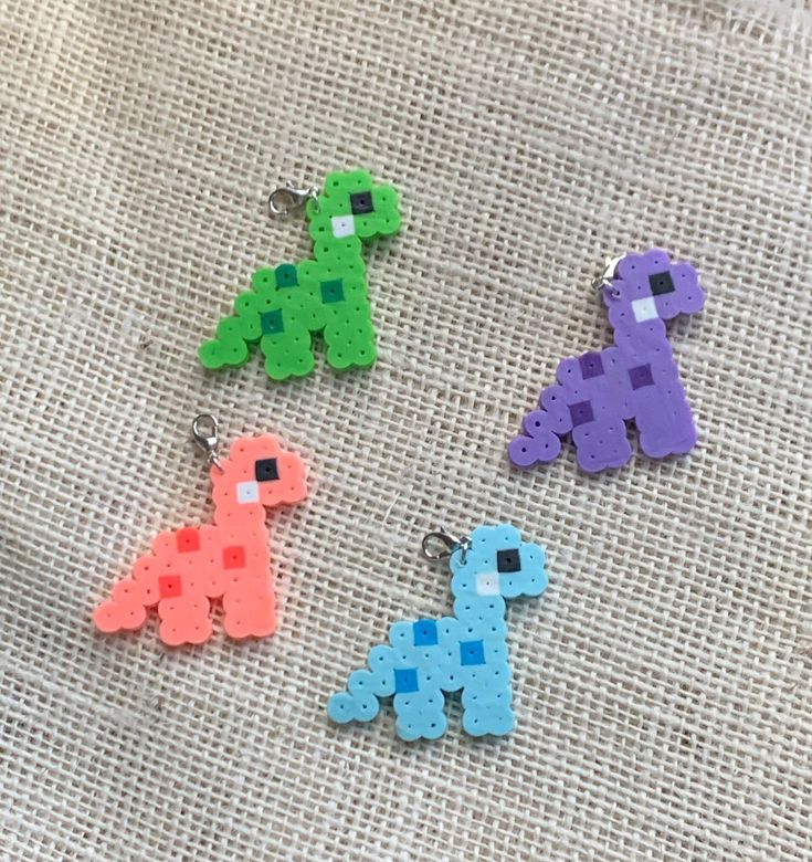 four different colored pixelo key chains sitting on top of a piece of cloth