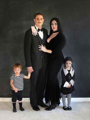 a man, woman and two children posing for a photo in front of a blackboard