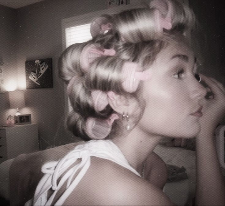 a woman with curly hair and pink bows in her hair is looking into the mirror