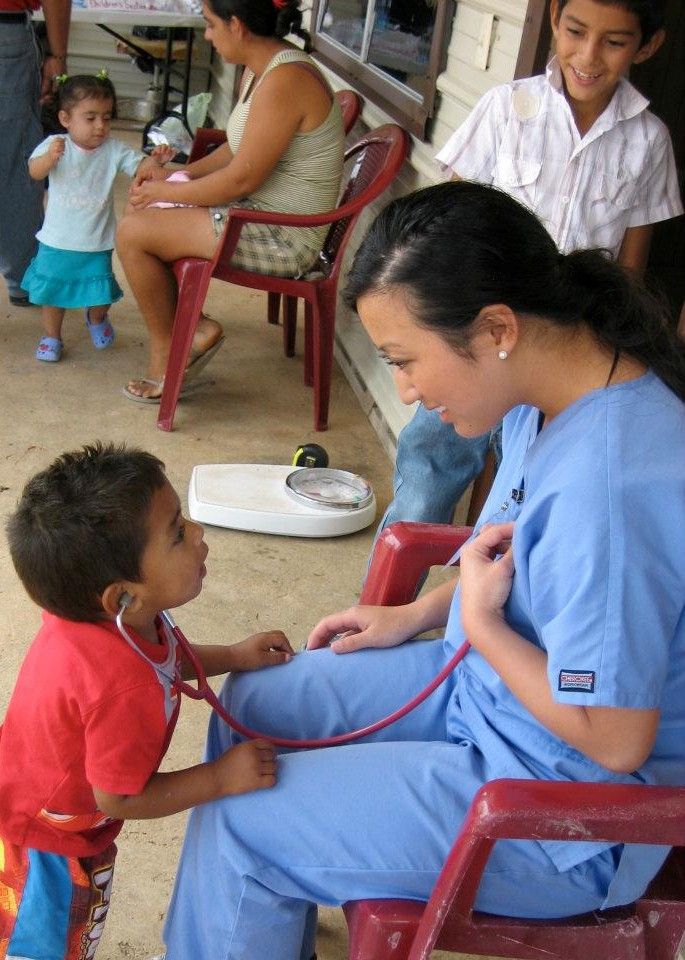 a woman in scrubs is listening to a little boy with a stethoscope