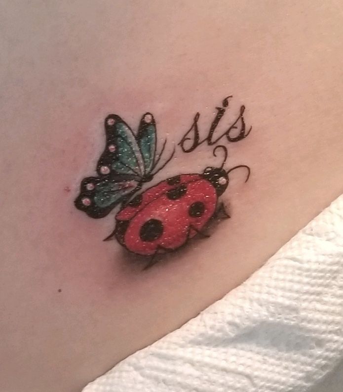 a ladybug tattoo with the word sis on it and a butterfly sitting on top