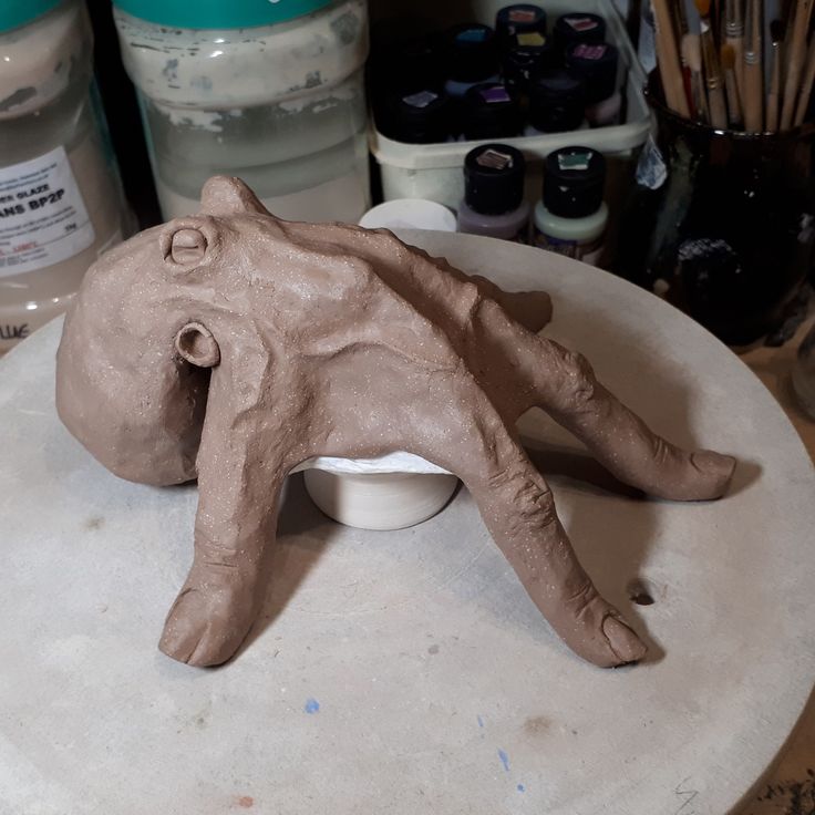 a clay animal laying on top of a white bowl