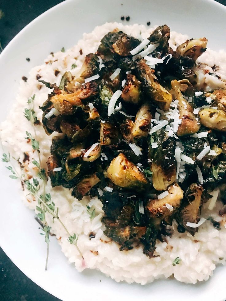 a white plate topped with rice covered in mushrooms and grated parmesan cheese