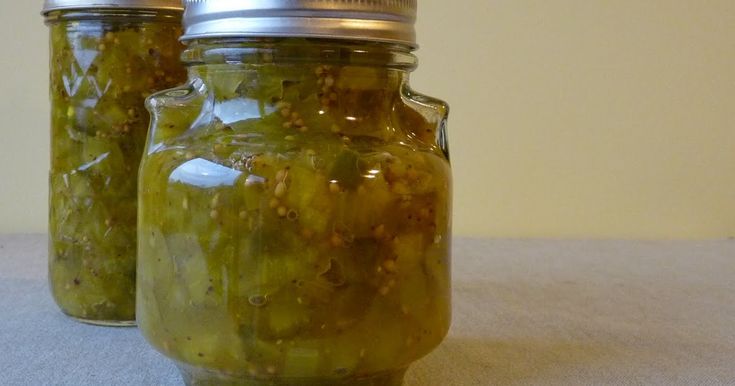 two jars filled with pickles sitting on top of a table