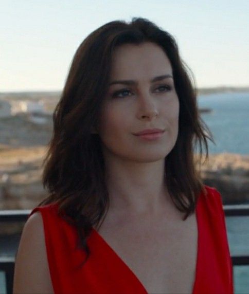 a woman in a red dress looking off into the distance while standing on a balcony