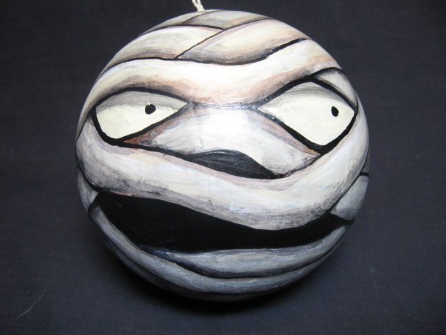 a ceramic ornament with a face painted on it's side, hanging from a rope