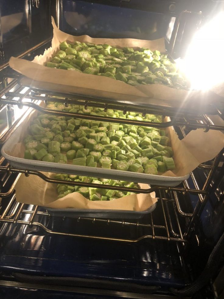 three pans filled with green vegetables cooking in the oven