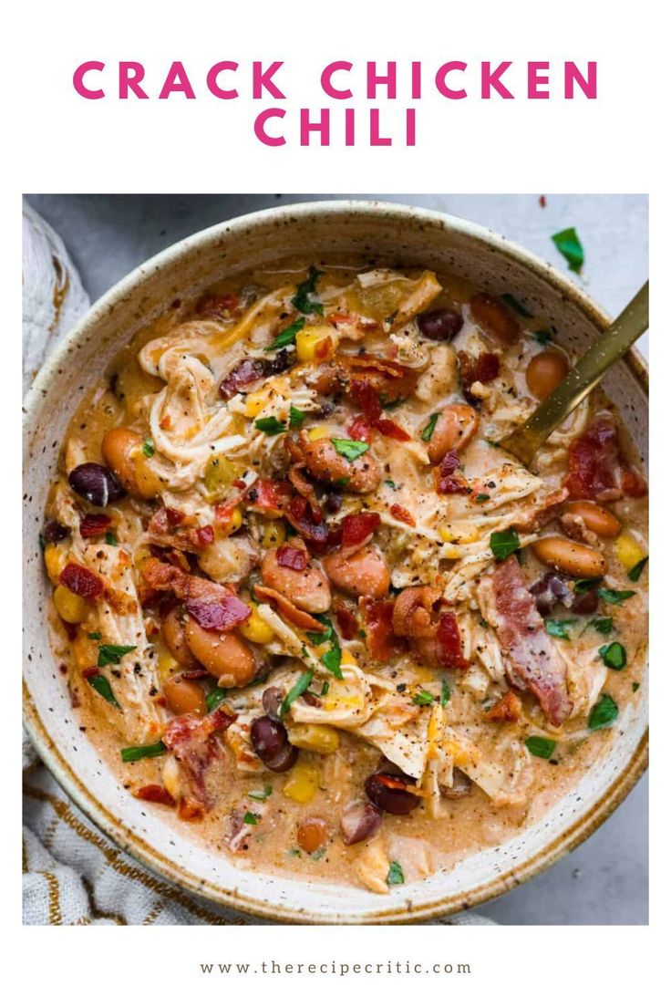 a bowl filled with chicken chili and beans on top of a white table next to a spoon