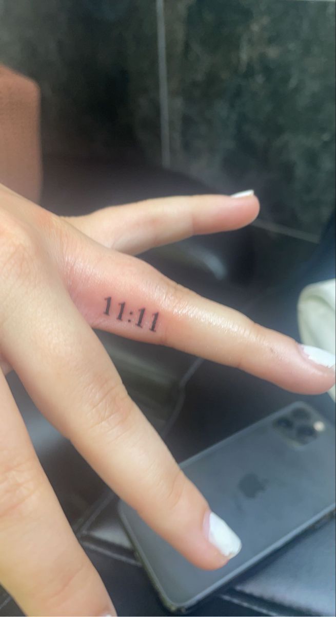 a woman's hand with the number 11 tattooed on her left thumb and fingers