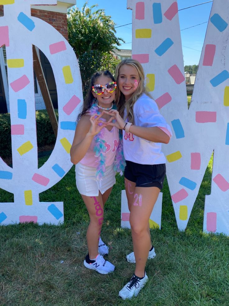 two girls standing next to each other in front of the letters d and m painted on them