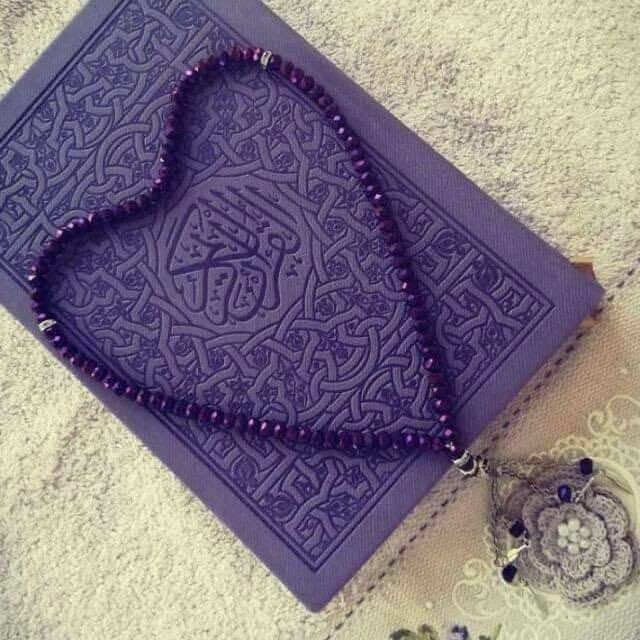 a purple beaded necklace sitting on top of a mat next to a small owl