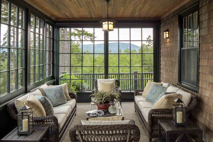 a screened porch with wicker furniture and large windows