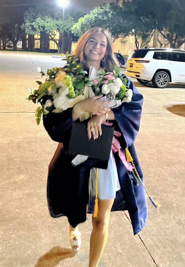 a woman is walking down the street carrying flowers