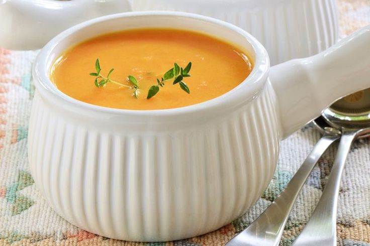 there is a white bowl filled with soup and two spoons on the table next to it