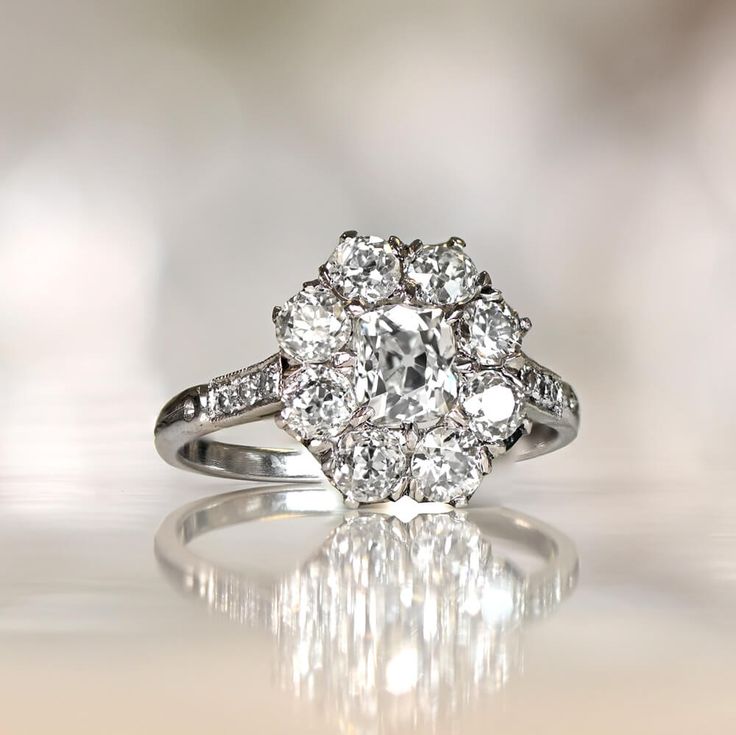 an old - fashioned diamond ring is shown on a white surface, with reflections in the background