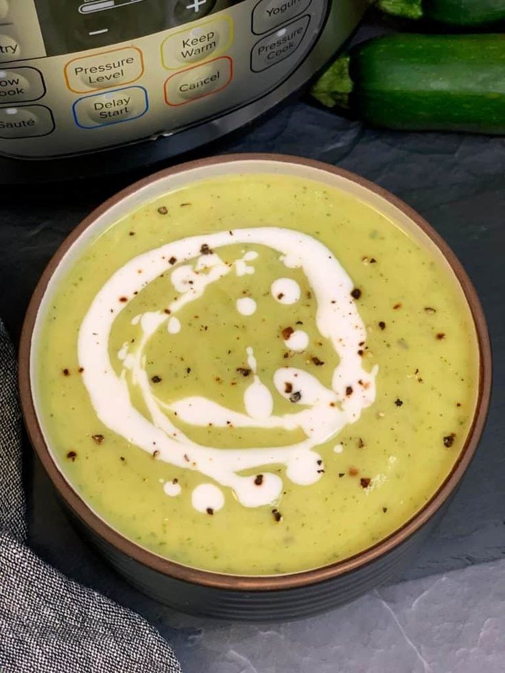 a bowl filled with soup next to an instant pressure cooker and cucumbers