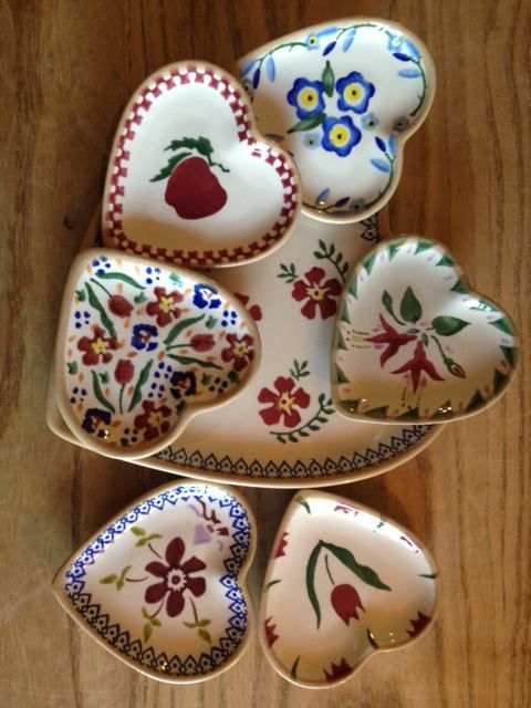 four heart shaped dishes are sitting on a wooden table with flowers and hearts painted on them