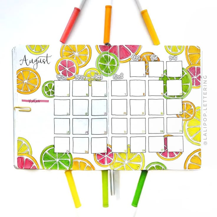 an orange and lime calendar with markers on the side, surrounded by lemons and grapefruit