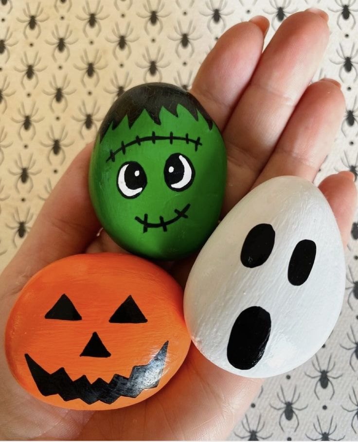 two rocks with faces painted on them in the palm of someone's hand