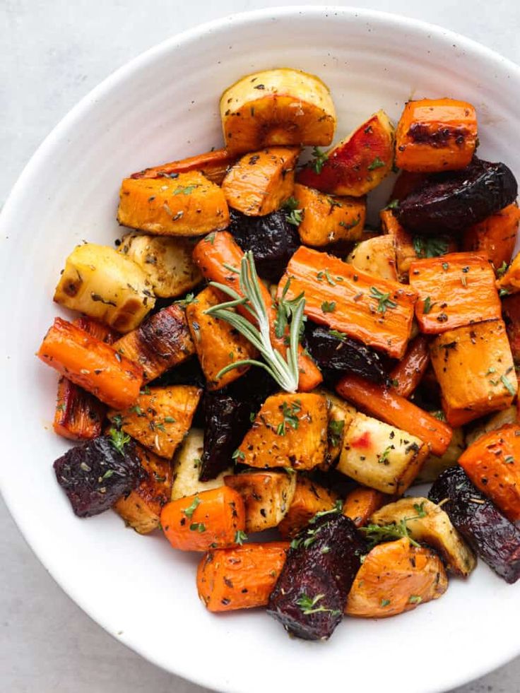 a white bowl filled with roasted carrots and potatoes