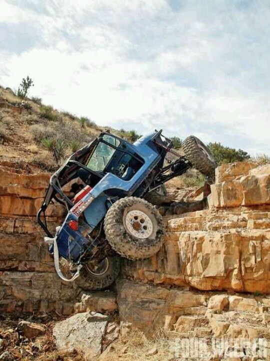 a blue jeep is jumping over some rocks