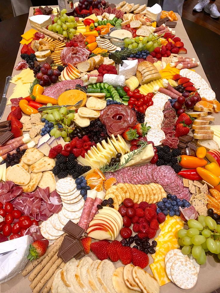 a long table covered with lots of different types of cheeses and fruits