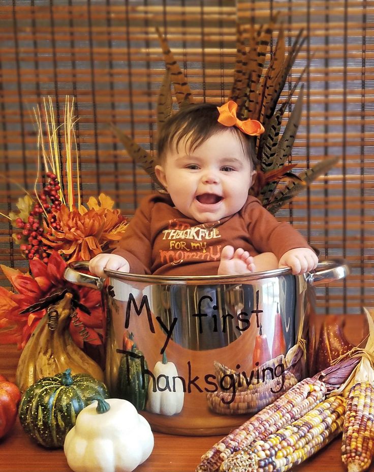 a baby is sitting in a pot surrounded by fall decorations and corn on the cob